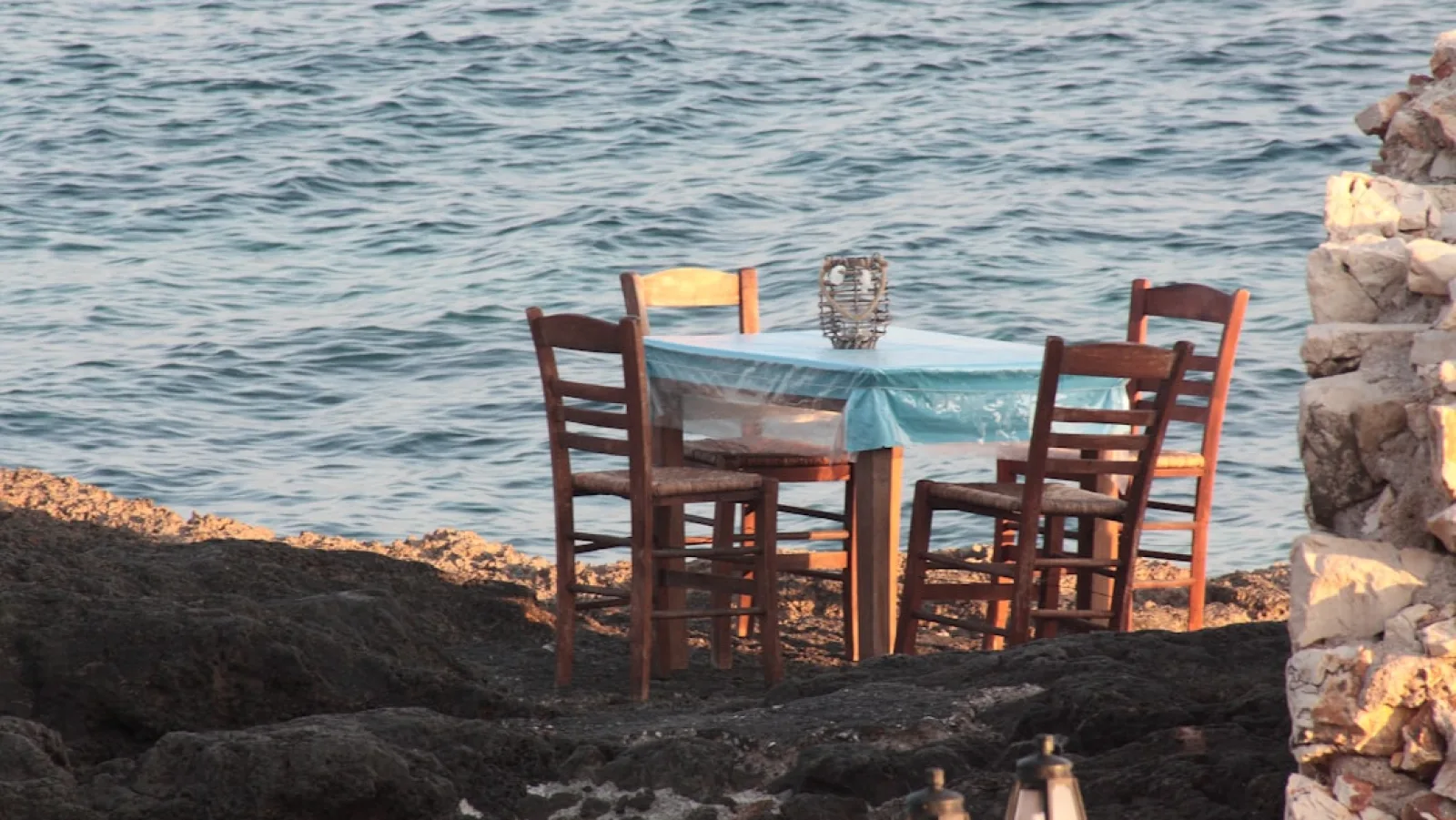a table and chairs sitting on a rocky shore