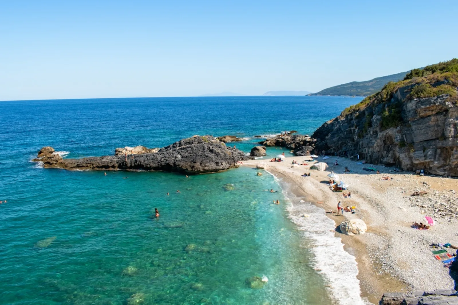 Rocky coastline with a pebble beach and clear blue water.